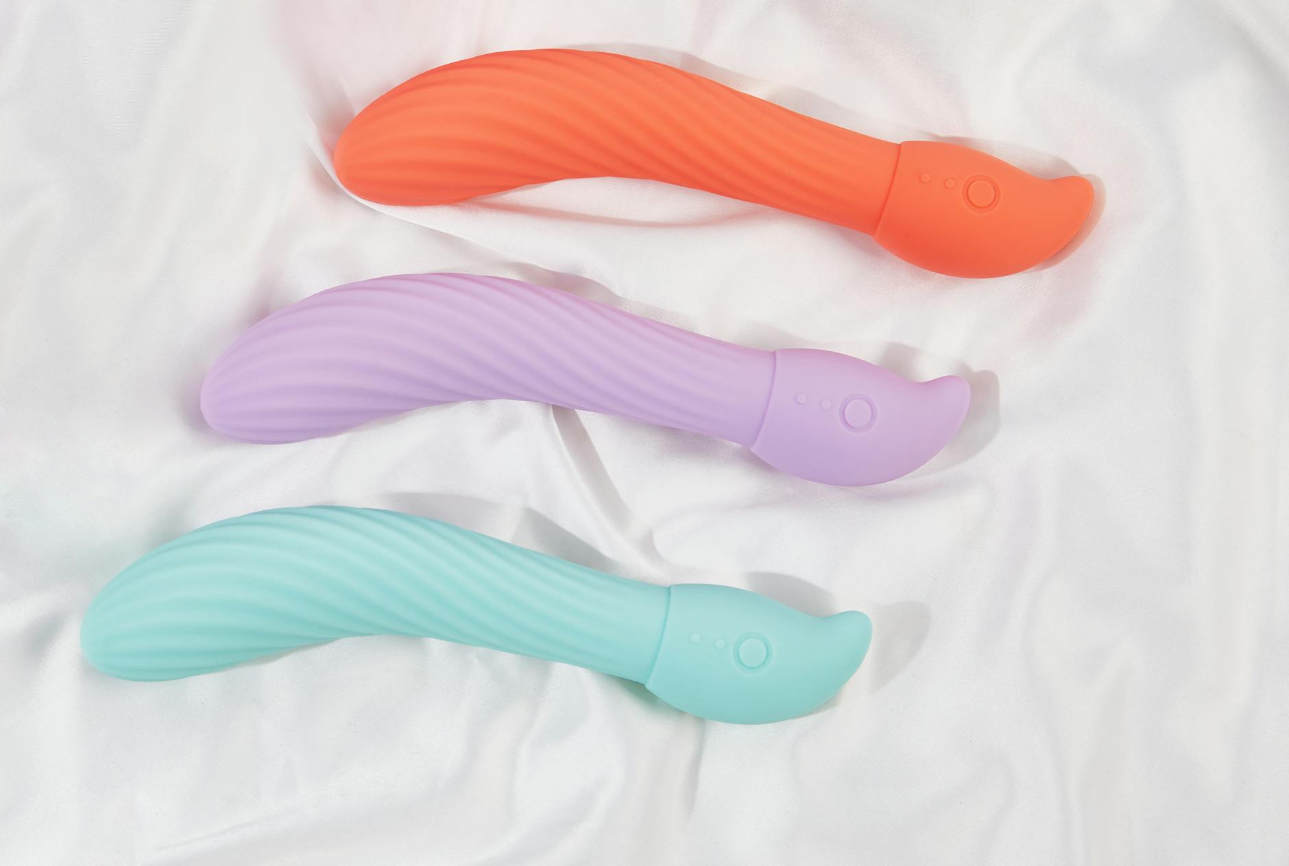 Three colorful lemon clitoral vibrators arranged on white fabric, highlighting their smooth texture and design