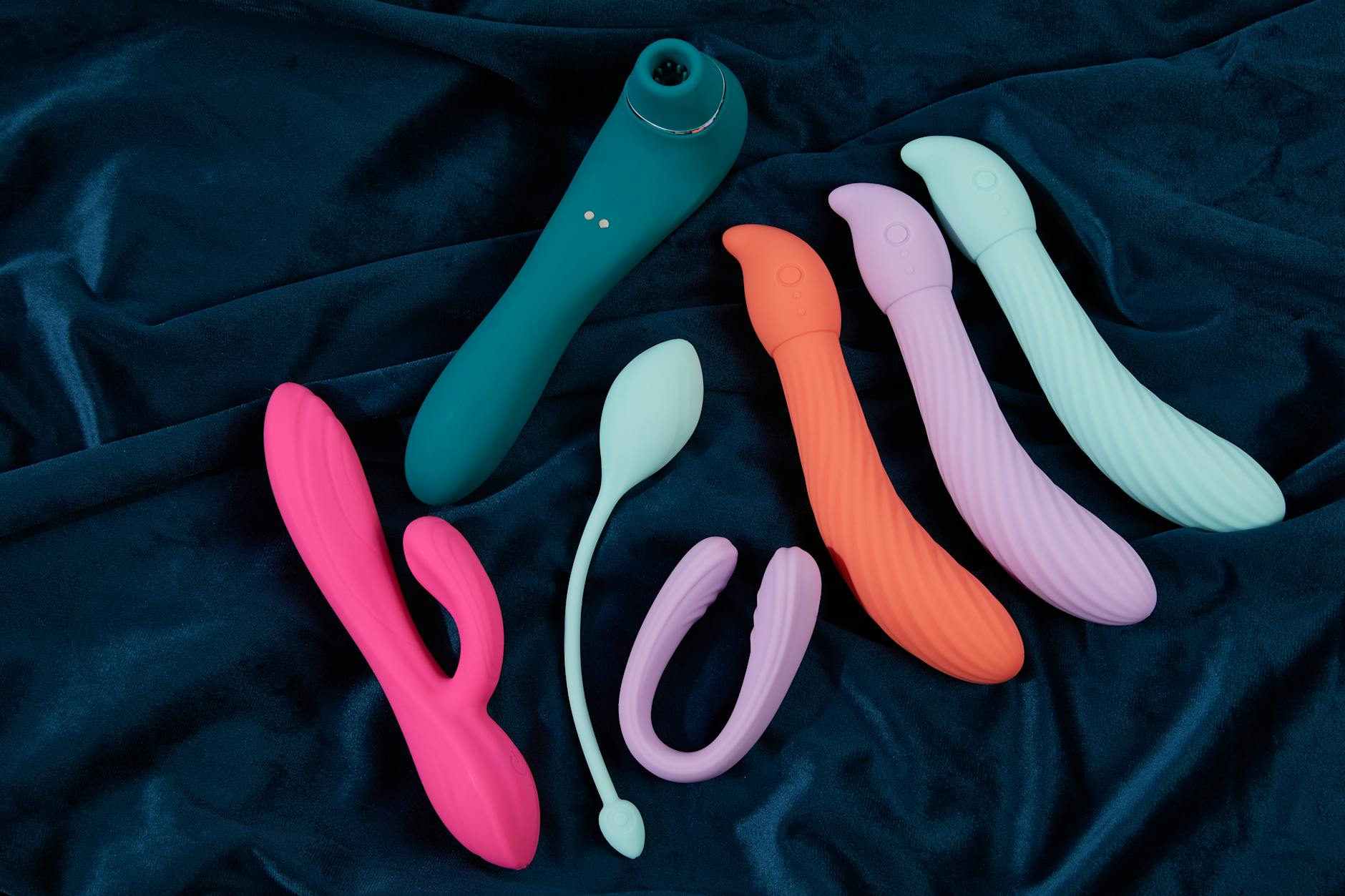 Hand holding an orange vibrator against a minimalistic purple backdrop, symbolizing reconnection to sensuality.