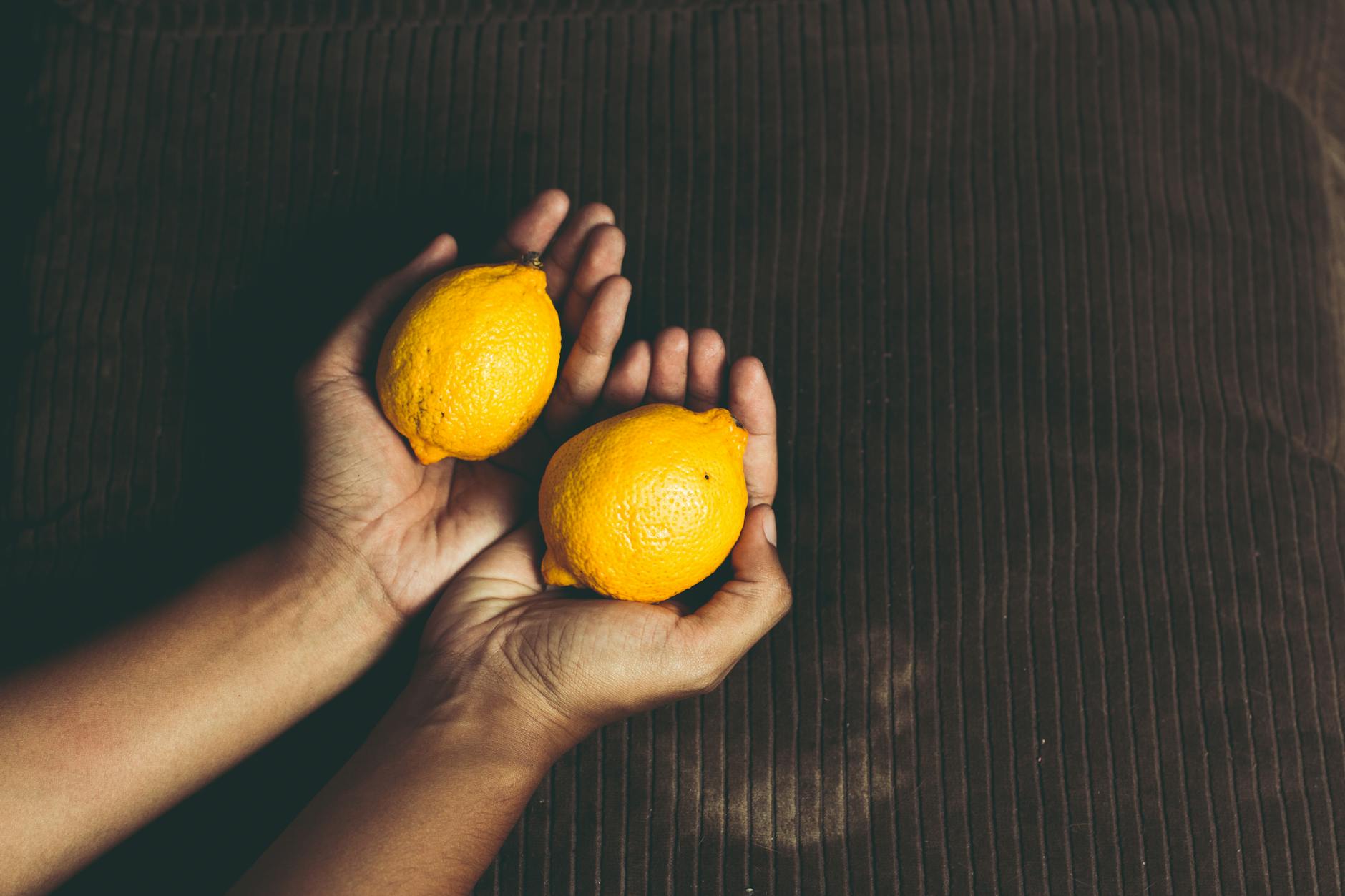 Two fresh lemons held in cupped hands, symbolizing shared pleasure and gentle introduction