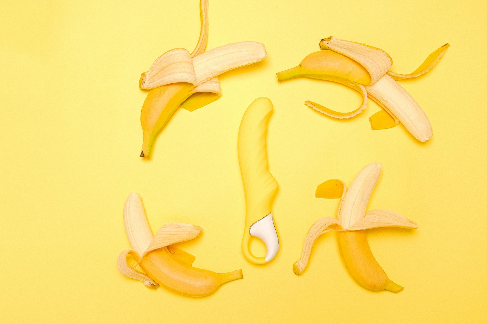 Yellow silicone lemon vibrator surrounded by fresh lemons on a yellow background