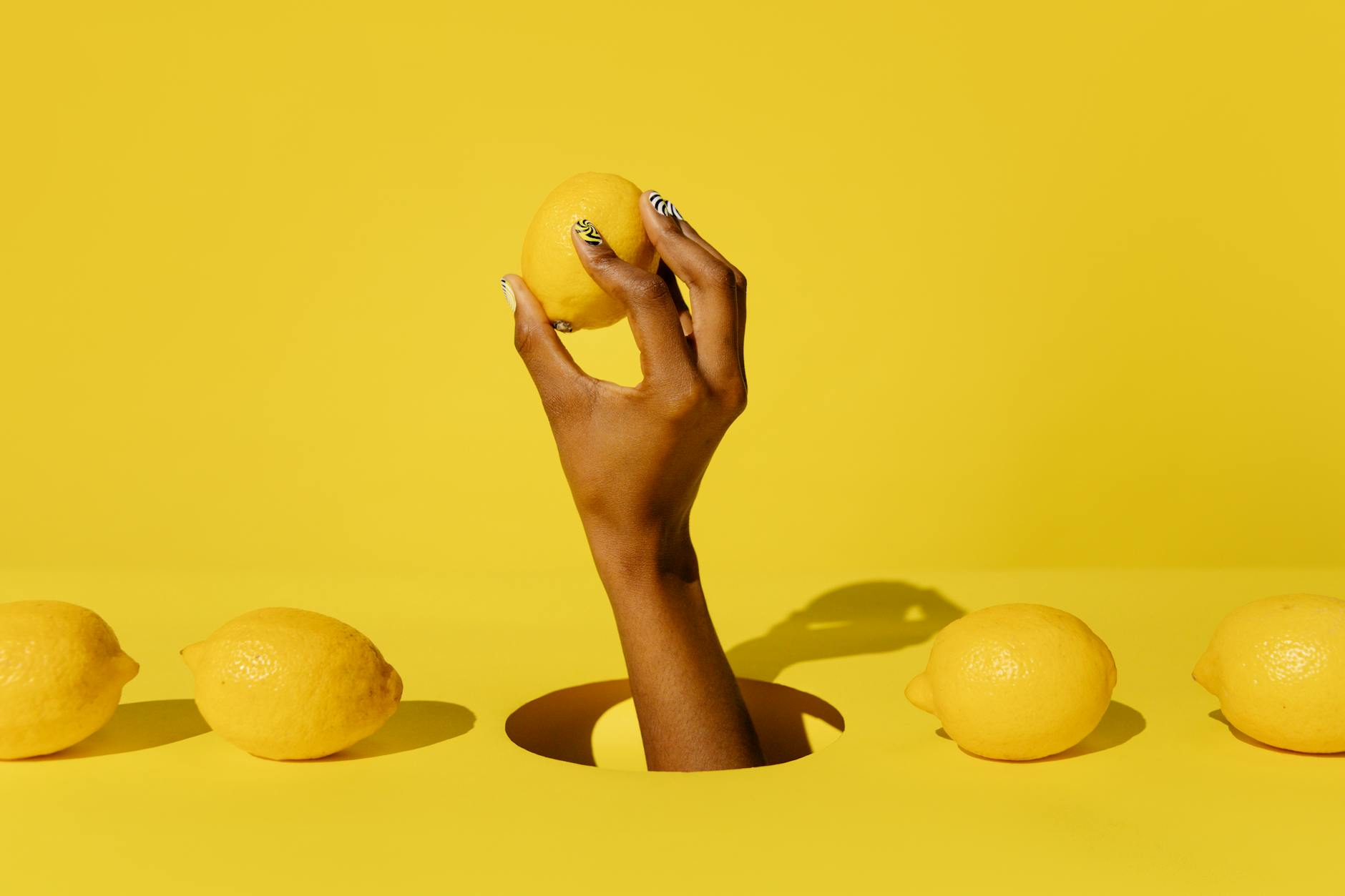 A hand holding a fresh lemon against a bright yellow background, symbolizing the fresh start of a new relationship