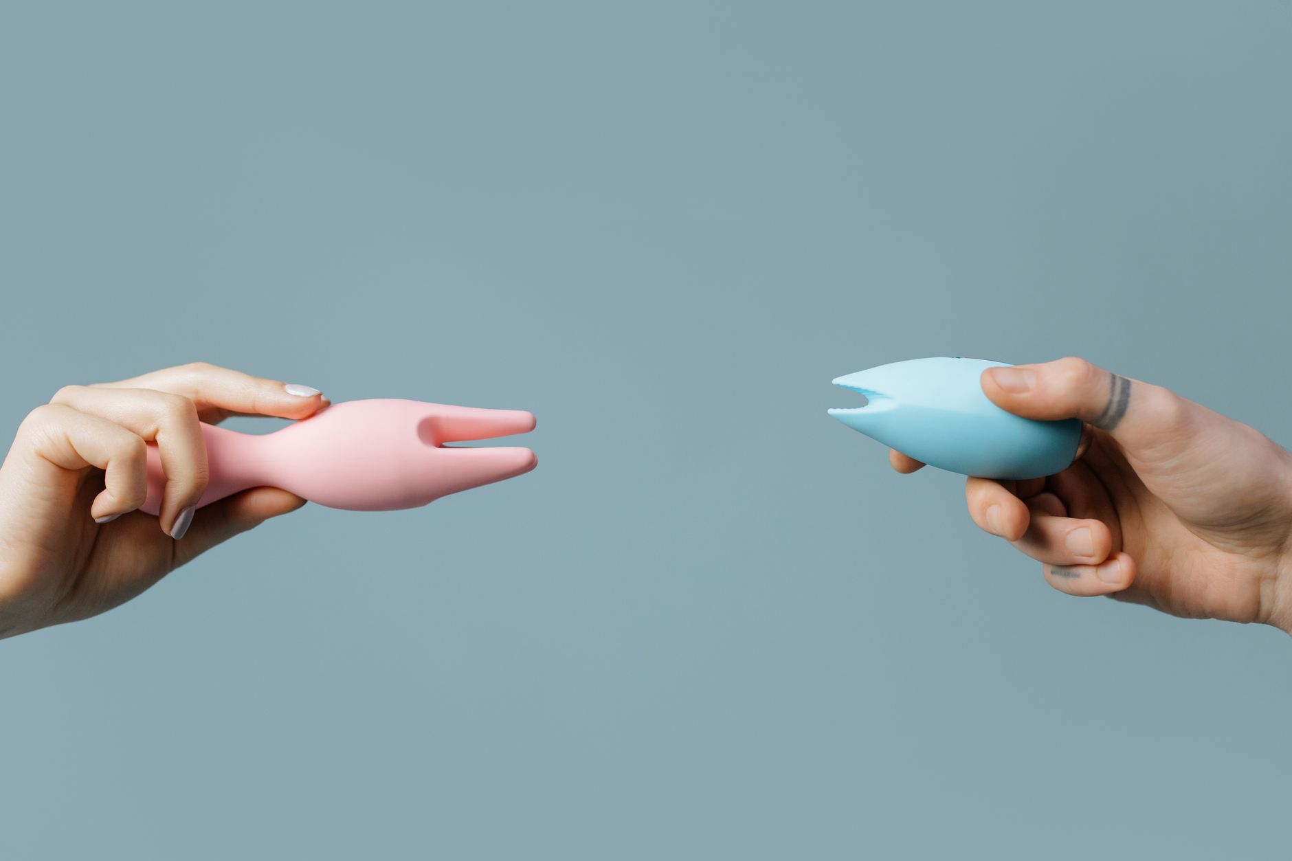 Two hands holding vibrators against a pastel background, representing tools for restoring sensation.