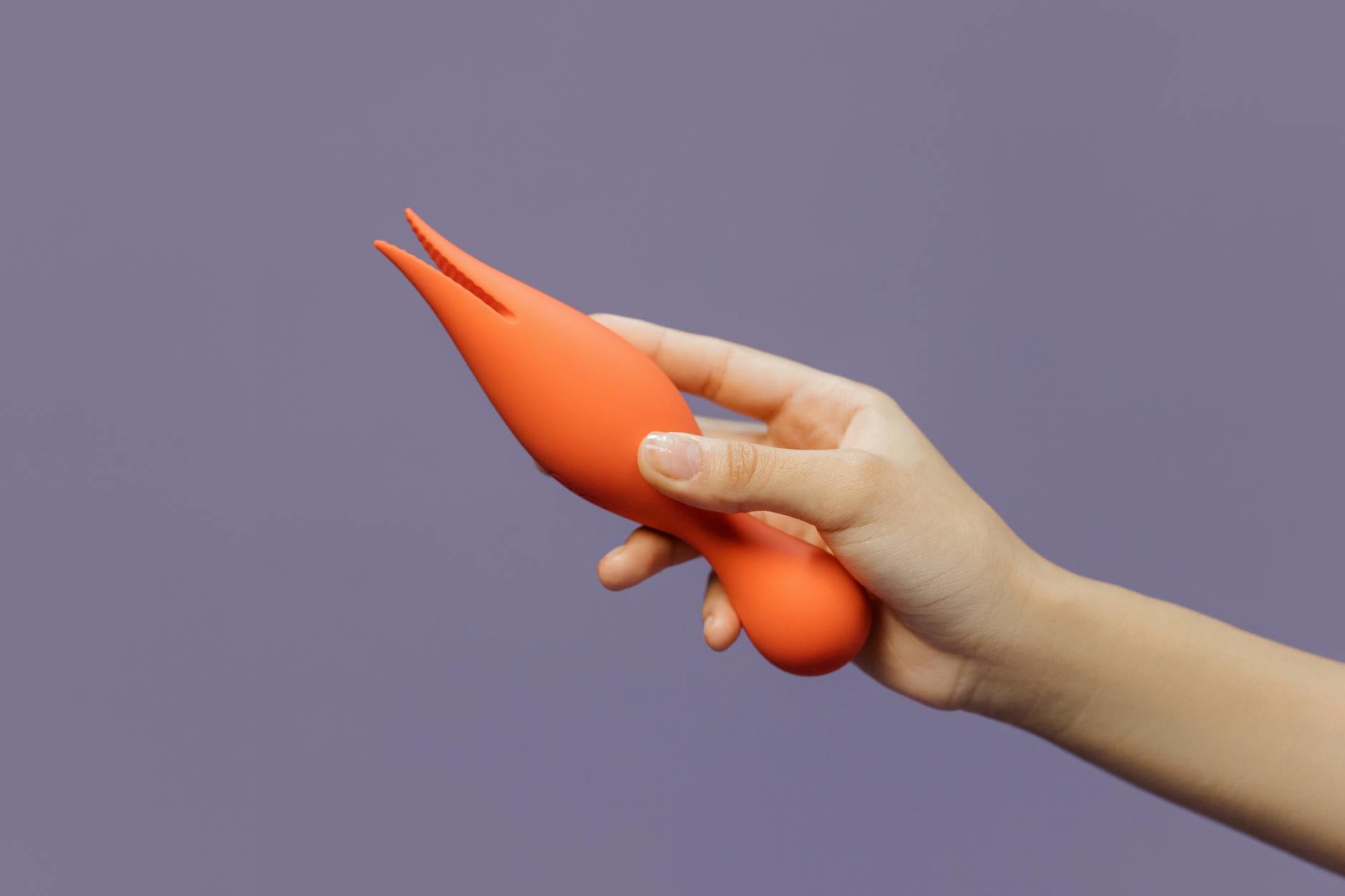 Hand holding a lemon vibrator against a minimalist purple backdrop, symbolizing modern intimacy after menopause