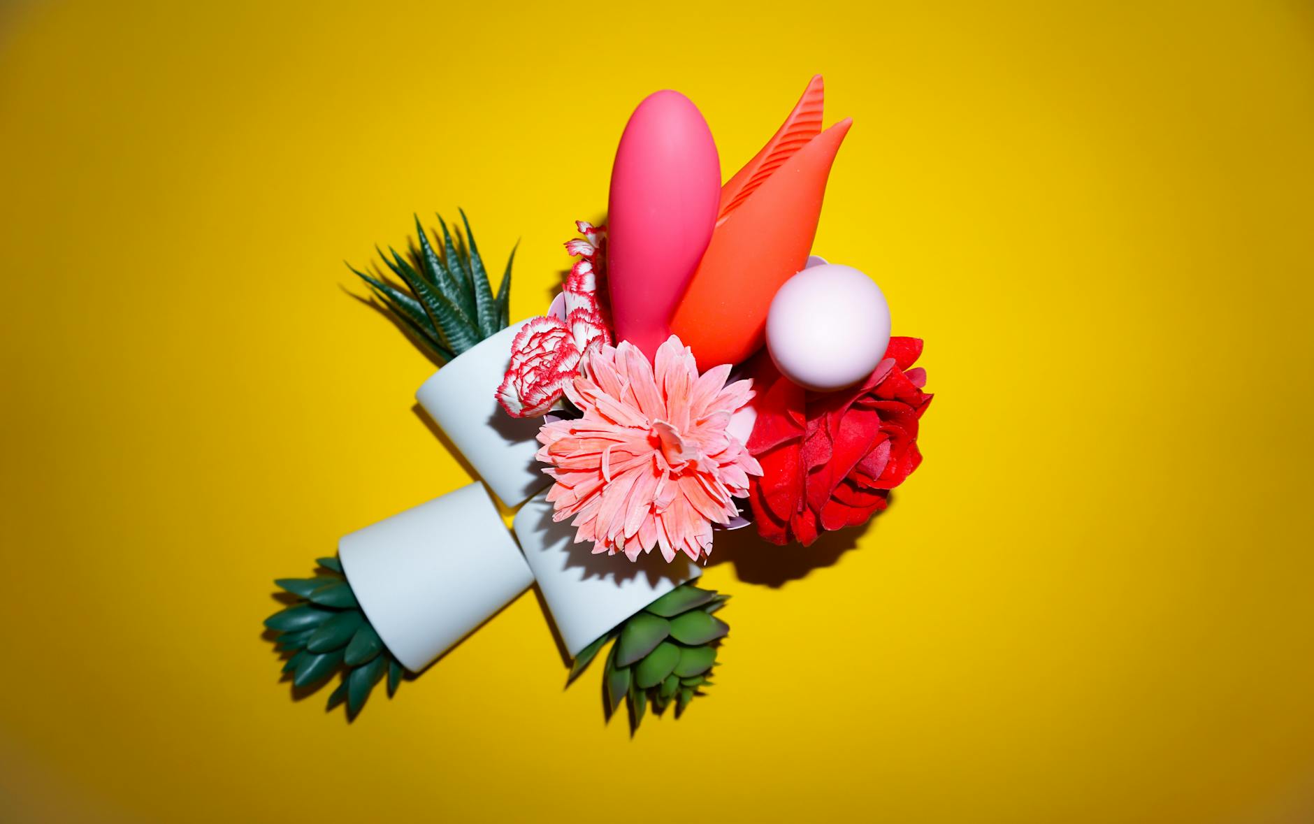 A blue lemon vibrator surrounded by flowers and citrus slices on a bright yellow surface.